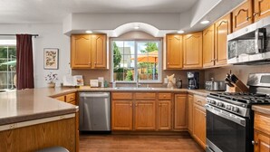 Una cocina moderna con armarios de madera, un lavavajillas de acero inoxidable, una estufa grande y una ventana con vistas al exterior.