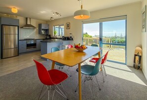 Eine moderne Küche mit Essbereich, großen Fenstern und einem Balkon.