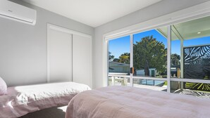 Een slaapkamer met twee bedden, een groot raam en uitzicht op buiten.