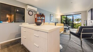 Een moderne keuken met een centraal eiland, een zithoek met een bank en een groot raam met uitzicht.