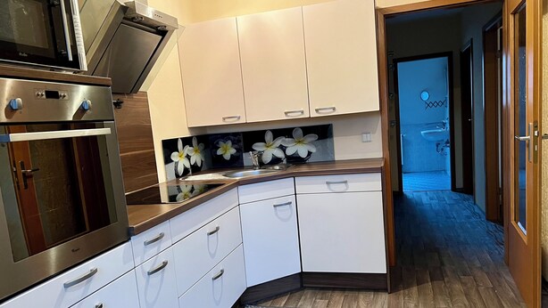 Una cocina moderna con armarios blancos, un horno de acero inoxidable y una encimera de madera.