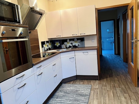 A modern kitchen with white cabinets, a stainless steel oven, and a wooden countertop.
