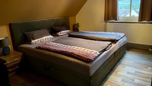 Un dormitorio con dos camas, una mesita de noche, una lámpara y una ventana con cortinas.