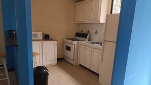 A kitchen with white cabinets, a stove, a microwave, and a trash can. - Alquiler de Departamento, excelente ubicación. (Managua)