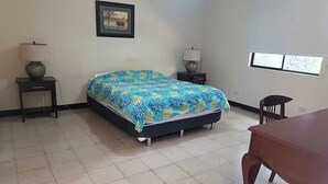 A bedroom with a bed, two bedside tables, a chair, and a wooden table. - Alquiler de Departamento, excelente ubicación. (Managua)