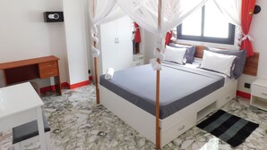 Een slaapkamer met een bed, een bureau, een kledingkast en een raam met gordijnen.