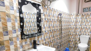 Een badkamer met betegelde wand, een wastafel, toilet en douche.