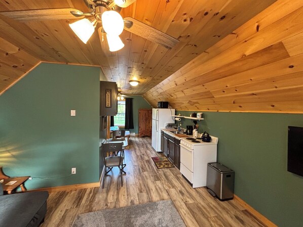 Una cocina acogedora con vigas de madera, una zona de comedor con mesa y sillas, y vistas al exterior.