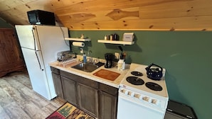 Cozinha compacta com geladeira, fogão, pia e armários de madeira.