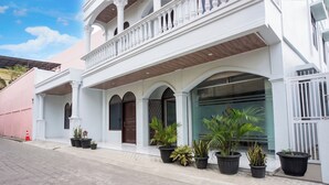 A two-story building with a balcony, arched windows, and potted plants on the ground floor. - Hotel O near Masjid Raya Al-Mashun forme (Medan)