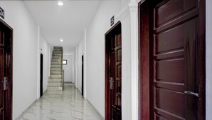A corridor with marble flooring, wooden doors, and a staircase leading to an upper level. - Hotel O near Masjid Raya Al-Mashun forme (Medan)