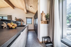 Eine moderne Küche mit Holzbalkendecke, einem Fenster mit Blick und einer kleinen Sitzecke.