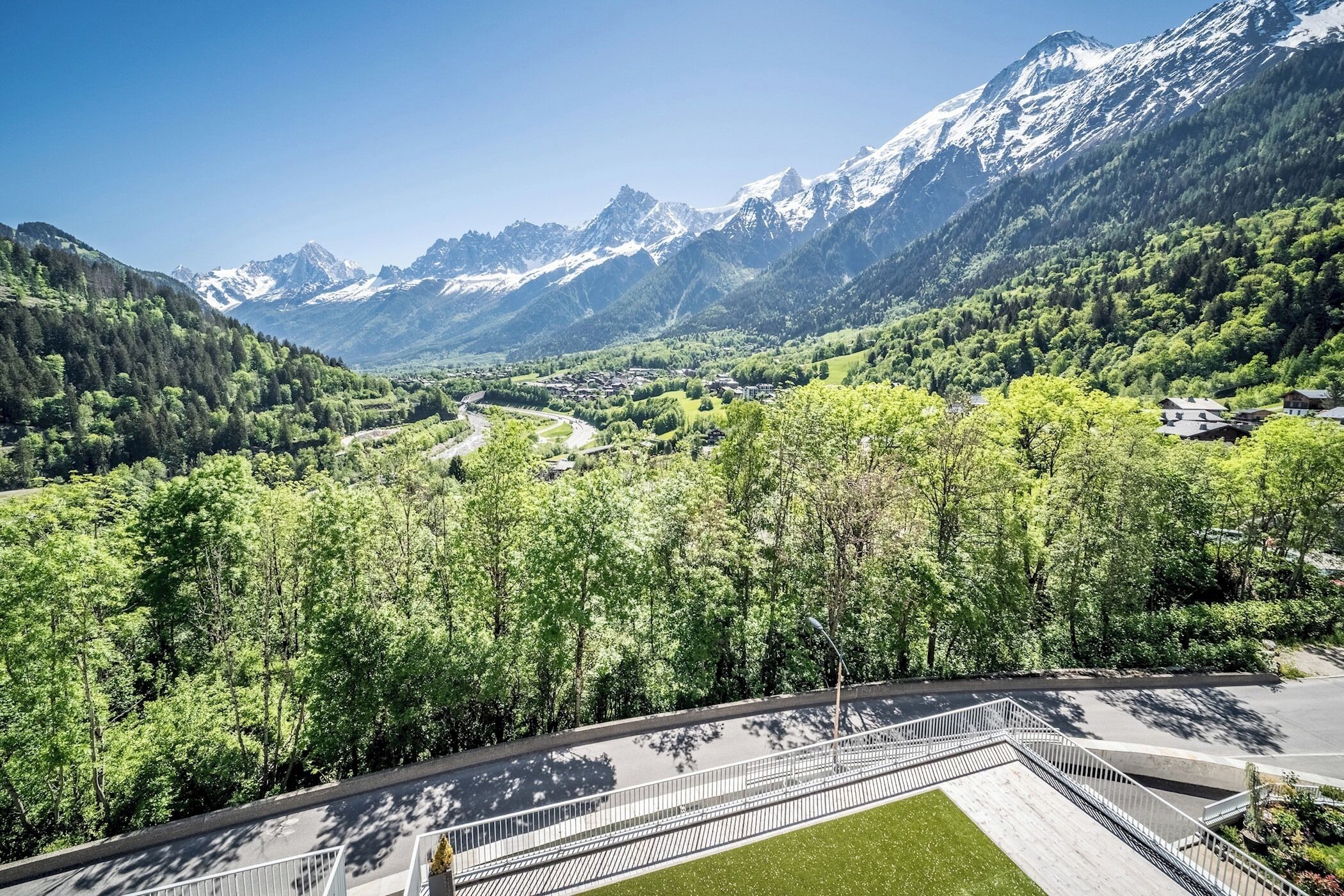 A mountainous landscape with a road, trees, and buildings.
