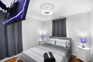 Ein modernes Schlafzimmer mit einem Bett, Nachttischen und einem Deckenventilator.
