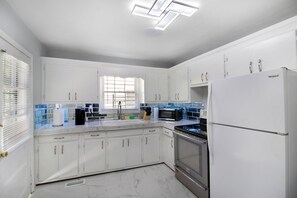 Eine moderne Küche mit weißen Schränken, einem Edelstahlherd, einer Mikrowelle und einem Whirlpool-Kühlschrank.