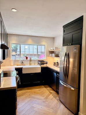 Eine moderne Küche mit einem großen Edelstahl-Kühlschrank, einem integrierten Geschirrspüler und einem Fenster mit Außenblick.