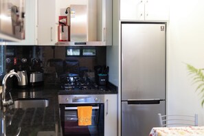 A kitchen with a stove, oven, refrigerator, and a sink. - Little house in Geres (Vieira do minho)