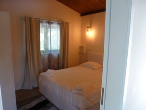 A bedroom with a bed, curtains, a bedside lamp, and a window. - Little house in Geres (Vieira do minho)