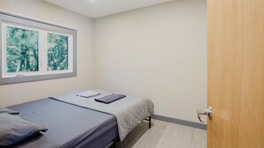 A bedroom with a bed, a window with a view, and a door. - 2-Bedroom Cottage #4 (Nobel)