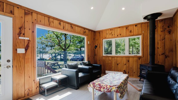A wooden-paneled room with a sofa, a table, and a fireplace. - 2-Bedroom Cottage #4 (Nobel)