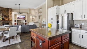 A modern kitchen with white cabinets, a central island, and a dining area with a sofa and chairs.