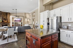 A modern kitchen with white cabinets, a central island, and a dining area with a sofa and chairs. - Ahwatukee Foothills Home | Heated Pool | Grill (Phoenix)