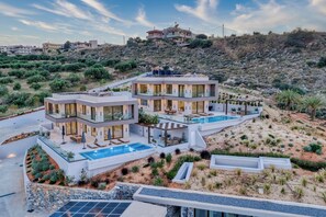 Una villa moderna con piscina, diversi balconi e un giardino curato.