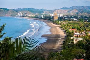 A coastal view with a beach, buildings, and hills.