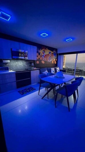 A modern kitchen with a dining area, a large TV, and a view of the city.