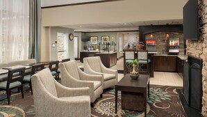 A hotel lobby with seating, a coffee bar, a fireplace, and a Coca-Cola vending machine.