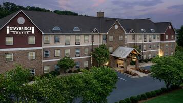 Un hotel Staybridge Suites con facciata in mattoni, diverse finestre e un prato ben curato.