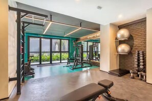 Ein Fitnessraum mit Trainingsgeräten, einer Bank und einer Wand voller Kurzhanteln.