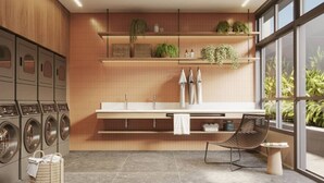 Una cocina moderna con electrodomésticos integrados, una zona de comedor con una silla y vistas a zonas verdes a través de grandes ventanales.