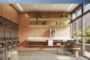 A modern kitchen with built-in appliances, a dining area with a chair, and a view of greenery through large windows. - Apartamento Confortável – Vila Olímpia (São Paulo)