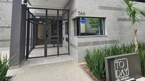 Un edificio moderno con entrada de vidrio, un letrero con el número '566' y un cartel que dice 'TO DAY'.