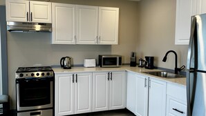 A modern kitchen with white cabinets, stainless steel appliances, and a tiled floor.