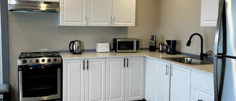 A modern kitchen with white cabinets, stainless steel appliances, and a tiled floor.