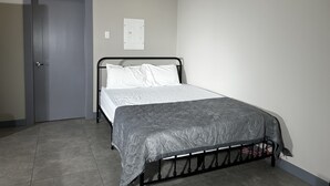 A bedroom with a bed, a door, and a light switch on the wall.