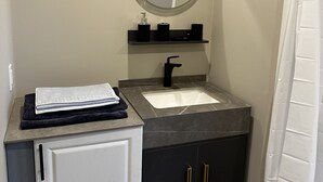 A bathroom with a white cabinet, a black sink, a mirror, and a shower curtain.