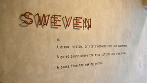 Een muur met de woorden 'SWIVEN' in houten letters en definities van dat woord eronder.