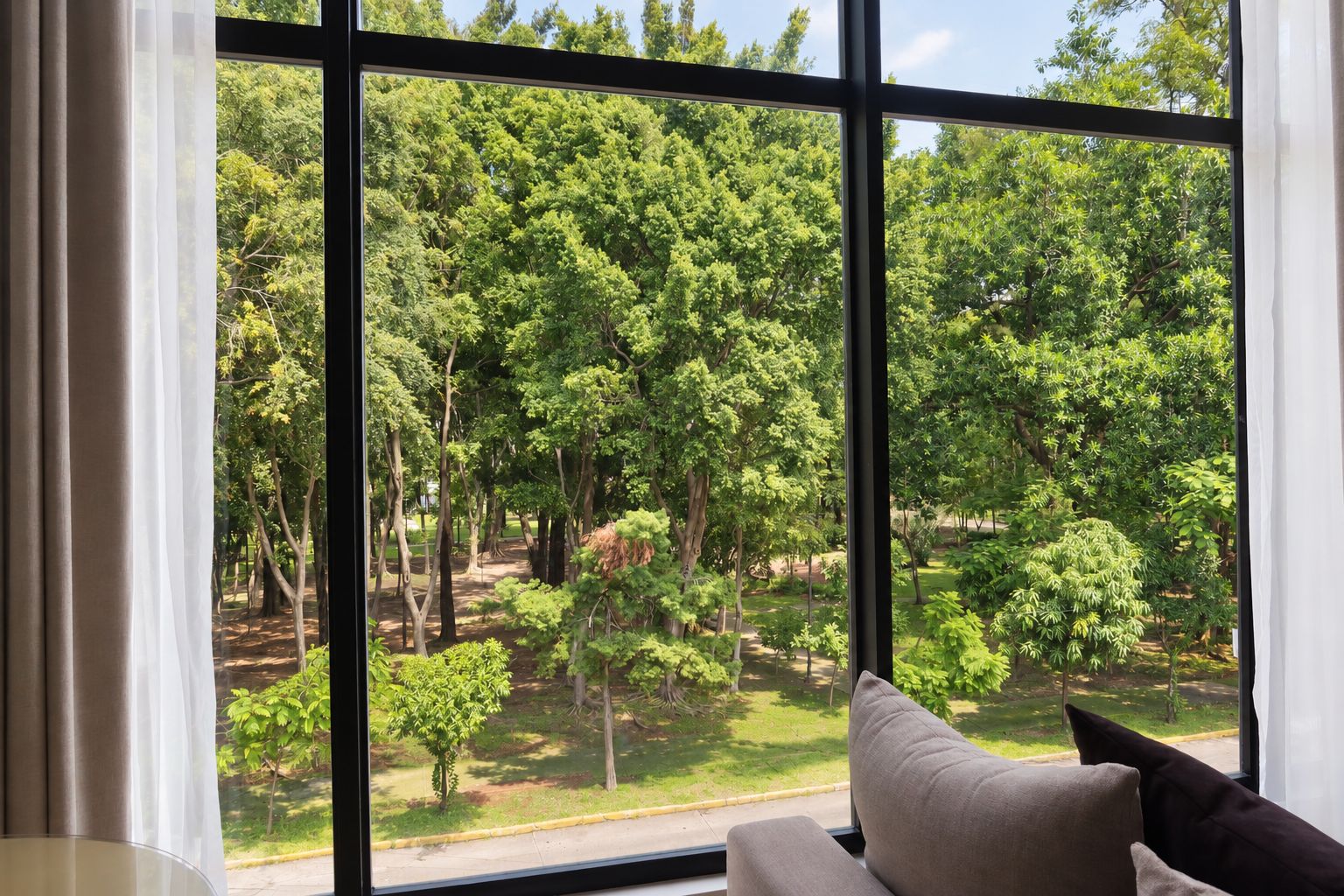 A room with a large window offering a view of a dense forest.