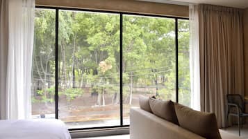Ein Zimmer mit großem Fenster, einer Couch, einem Sessel und einem Bett.
