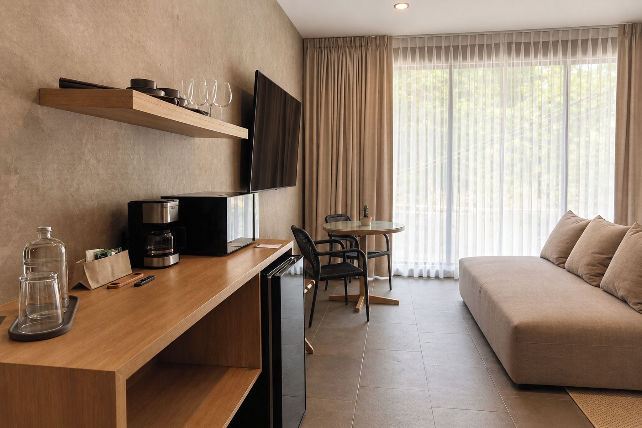 Ein modernes Hotelzimmer mit einem Holztisch, einem Flachbildfernseher, einer Couch und einer Essecke mit Tisch und Stühlen.