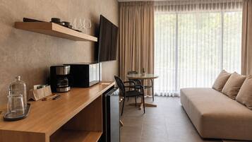 Ein modernes Hotelzimmer mit einem Holztisch, einem Flachbildfernseher, einer Couch und einer Essecke mit Tisch und Stühlen.