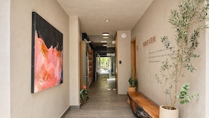 Un pasillo con un banco, un cuadro abstracto grande y una pared con una planta y texto.