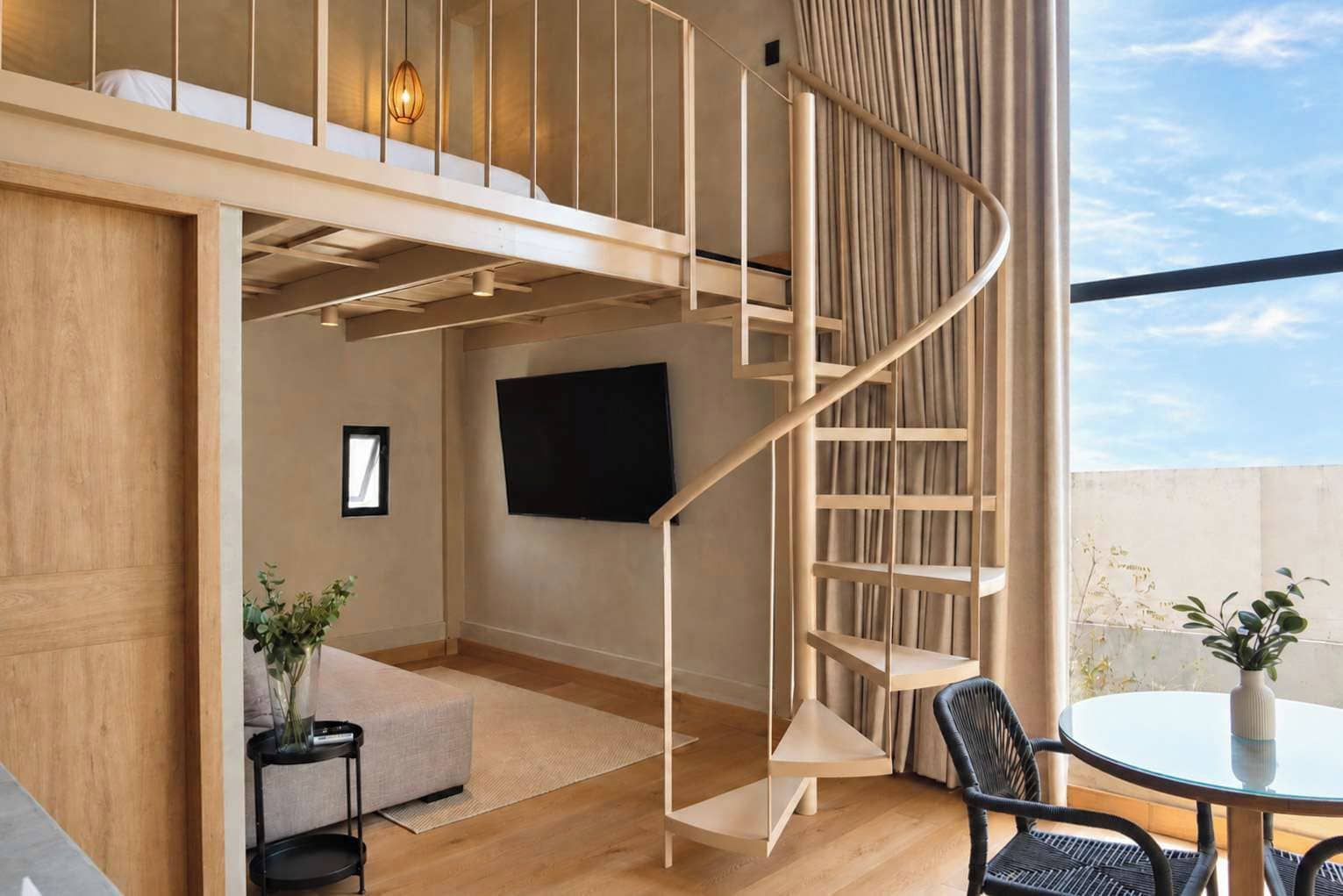 A modern interior with a spiral staircase, a flat-screen TV, and a round dining table.