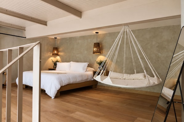A bedroom with a bed, a hanging chair, and two wall-mounted lamps. - SWEVEN Hotel Boutique (Guadalajara)