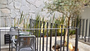 A patio area with a stone wall, a metal fence, and outdoor furniture including a table and chairs. - SWEVEN Hotel Boutique (Guadalajara)