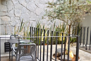 A patio area with a stone wall, a metal fence, and outdoor furniture including a table and chairs.