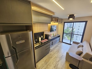 Eine moderne Küche mit Kühlschrank, Herd und Spüle, ein Essbereich mit einer Couch und ein Balkon mit Aussicht.
